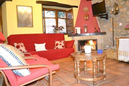 a living room with a red couch and a fireplace at 2 bedrooms chalet with terrace and wifi at Orena in Oreña