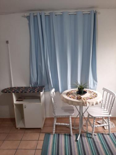 uma mesa e cadeiras num quarto com cortinas azuis em Pousada Goulart em Blumenau