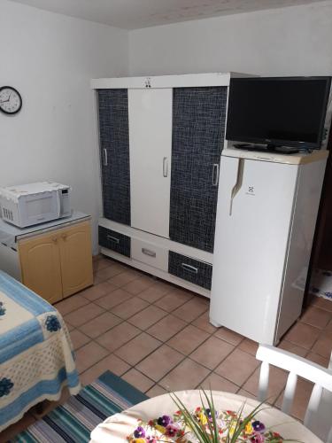 a kitchen with a white refrigerator and a tv at Pousada Goulart in Blumenau