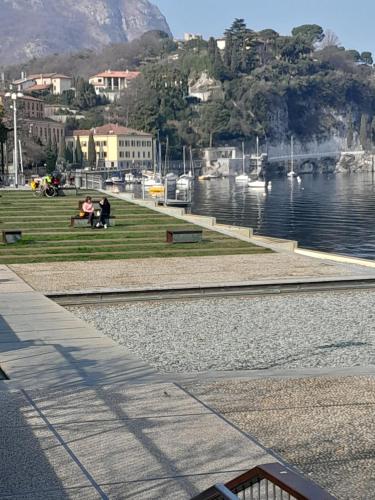 two people sitting on a bench next to a body of water at L'Incanto dell'Airone in Malgrate