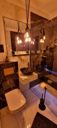 a bathroom with a toilet and a sink with lights at Happy time together apartament z Jacuzzi in Wojkowice