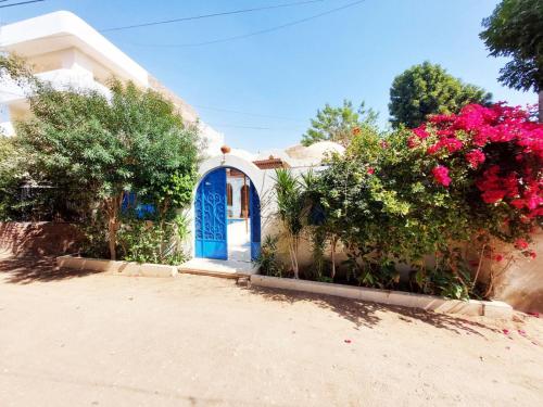 une petite maison avec une porte bleue et des fleurs dans l'établissement Villa Cleopatra Luxor west bank, à Louxor