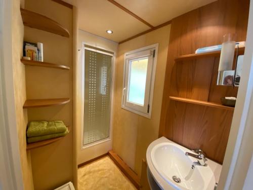 a bathroom with a sink and a window at Charmant Mobile-home 6 personnes sur terrain privé à 200 m de la plage - PADRIG in Ploemeur
