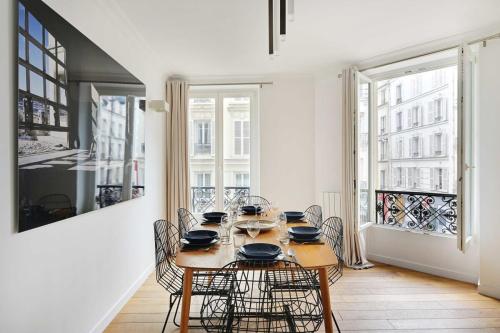 une salle à manger avec une table, des chaises et des fenêtres dans l'établissement Renovated and modern 4BD for 12 guests, à Paris