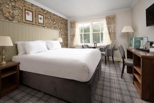 a hotel room with a large bed and a desk at The Ullswater Inn- The Inn Collection Group in Glenridding