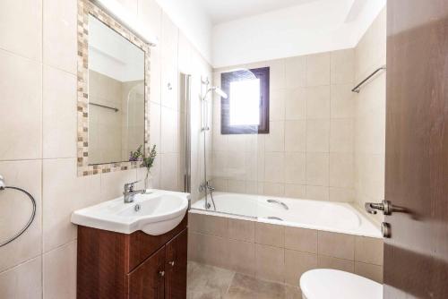 een badkamer met een wastafel, een bad en een toilet bij Villa Michael Coral in Peyia