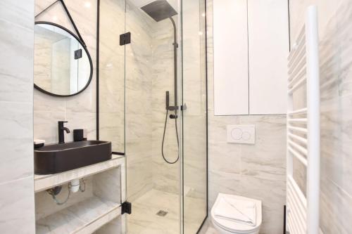 une salle de bain avec une douche avec un lavabo et des toilettes dans l'établissement Renovated 2BD apartment in Parc Belleville, à Paris
