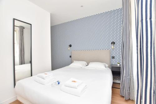 une chambre avec un lit blanc et un miroir dans l'établissement Renovated 2BD apartment in Parc Belleville, à Paris