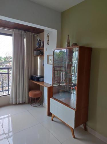 a room with a glass cabinet with a desk and a window at Apto com conforto que você precisa. in Goiânia