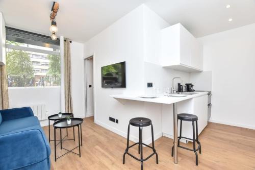 - une cuisine et un salon avec un canapé bleu et un tabouret dans l'établissement Renovated 2BD apartment in Parc Belleville, à Paris