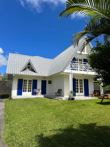 una casa bianca con porte blu e una palma di Villa entre Mer et Montagne a Le Tampon