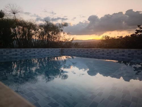 una piscina con puesta de sol en el fondo en Amonitas Glamping Deluxe en Tinjacá