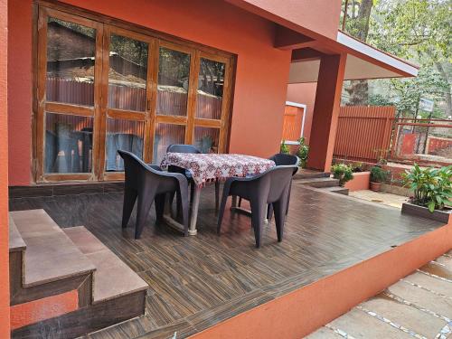 un tavolo e sedie seduti su una terrazza con una casa di Nivritti Villa a Matheran