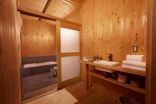 ein Bad mit Holzwänden und einem Waschbecken in einem Zimmer in der Unterkunft 結家 -MUSUBIYA- in Kawagoe