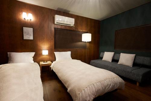 una camera d'albergo con due letti e un divano di 結家 -MUSUBIYA- a Kawagoe