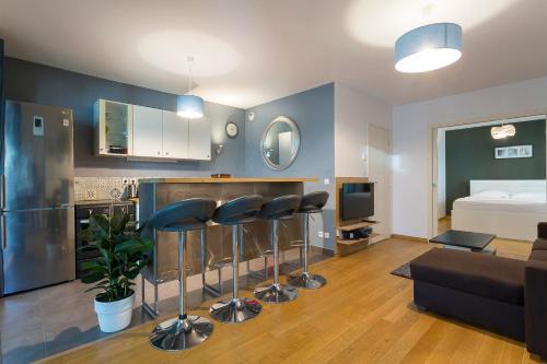 a living room with a couch and a kitchen with stools at Hamac Suites - Le confluence terrasse garage-4pers in Lyon