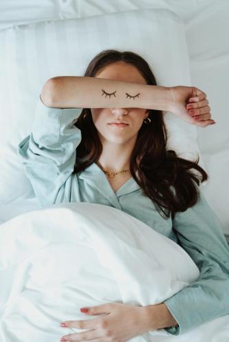 a woman laying in bed with a tattoo of two birds on her arm at Hotel Janssen in Valkenburg