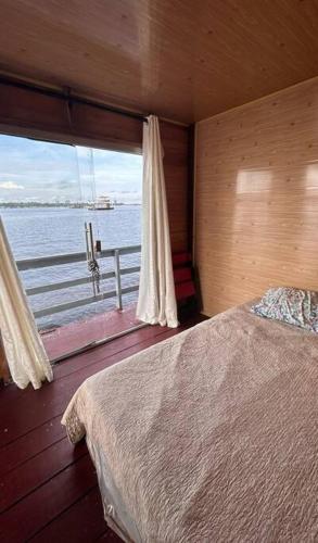 Schlafzimmer mit einem Bett und Blick auf das Wasser in der Unterkunft Flutuante Long Beach Manaus Am in Manaus