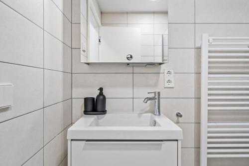 um lavatório branco numa casa de banho com azulejos brancos em Classy Studio next to Belval Shopping Plaza-ID-176 em Esch-sur-Alzette