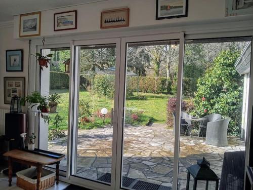 una puerta corredera de cristal abierta con vistas al jardín en Ty Clafout Vannetaise parking wifi linge non inclus, en Saint-Nolff