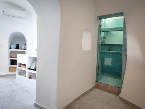baño con ducha acristalada en una pared blanca en EL PATRON SANTORINI en Fira