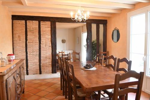a dining room with a wooden table and chairs at Maison à 6 km de Eymet piscine chauffée. in Roumagne
