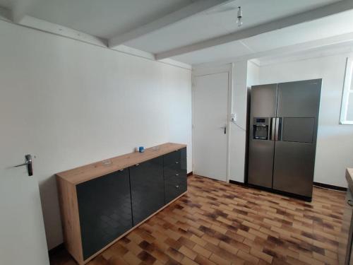 a kitchen with a refrigerator and a wooden floor at Maison à 6 km de Eymet piscine chauffée. in Roumagne