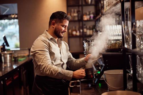 a man standing behind a bar mixing a drink at Van der Valk Hotel Stein Urmond in Urmond