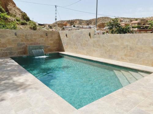 una piscina con una pared de piedra en 3 bedrooms property with private pool at Cortes y Graena, en Graena