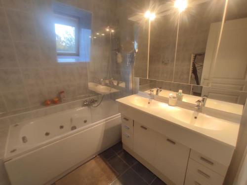 La salle de bains est pourvue de 2 lavabos, d'une baignoire et d'un miroir. dans l'établissement Maison pour 6 personnes au calme, à Pornichet