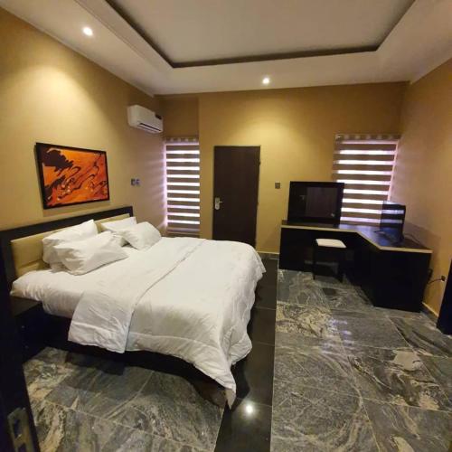 - une chambre avec un lit, un bureau et une télévision dans l'établissement Safari Court, à Abuja