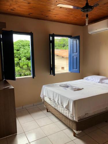 a bedroom with a bed and two windows at Pousada Brilho da Chapada New in Lençóis