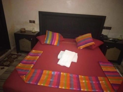 een rood bed met kleurrijke lakens en kussens bij DAR HIBa in Marrakesh