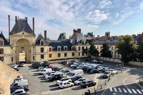 un parking avec des voitures garées devant un bâtiment dans l'établissement Suites Rive Gauche - Vue Château Fontainebleau - Chez Lydia, à Fontainebleau