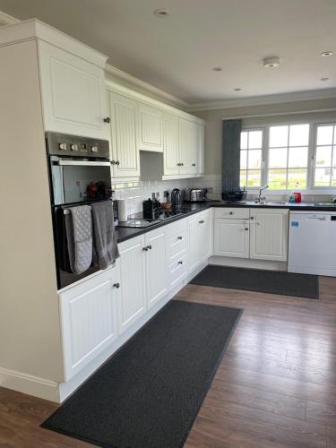 a large white kitchen with white cabinets and appliances at OAK LODGE in Tillingham