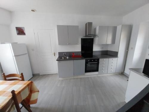 a kitchen with white cabinets and a stove and refrigerator at Agréable maison 5 couchages in Prunay-le-Gillon