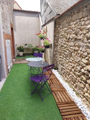 un patio avec une table et des chaises sur l'herbe dans l'établissement Agréable maison 5 couchages, à Prunay-le-Gillon