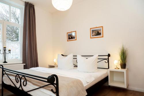 un dormitorio con una cama con sábanas y almohadas blancas en Villa Zur Alten Post, en Kühlungsborn