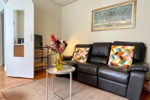 un salon avec un canapé en cuir noir et une table dans l'établissement Fontainebleau - Chez Marguerite, à Fontainebleau