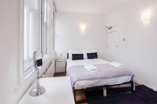 a white bedroom with a bed and a window at City Superhost - Northern Quarter Loft Conversion in Manchester