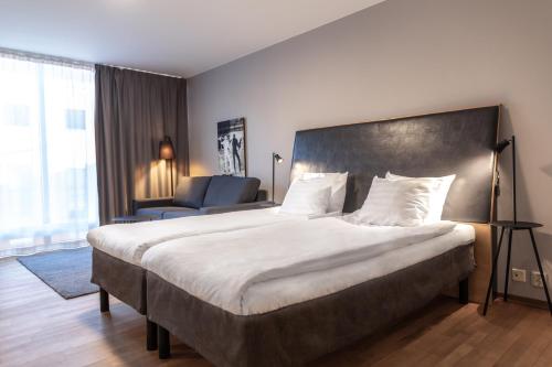 a hotel room with a large bed and a chair at Quality Hotel 11 & Eriksbergshallen in Gothenburg