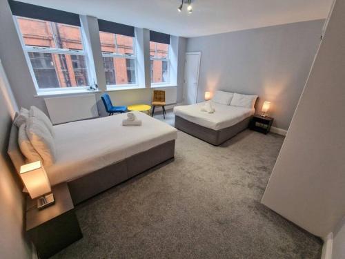 a hotel room with two beds and a chair at Canal Street Apartment in Manchester