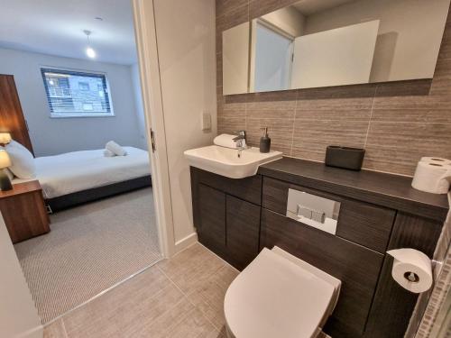 a bathroom with a sink and a toilet and a bed at Free Parking - Stunning Canal Facing Apartment in Manchester