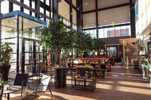 a restaurant with tables and chairs and trees in a building at Quality Hotel 11 & Eriksbergshallen in Gothenburg