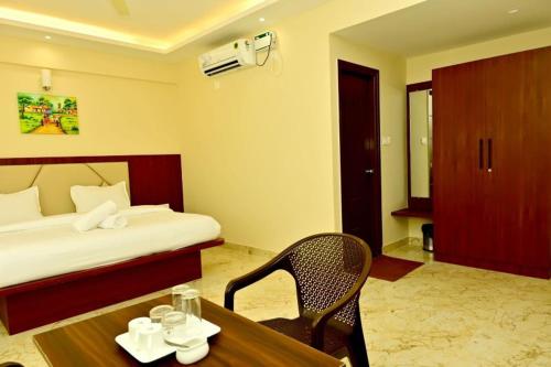 a hotel room with a bed and a table and chair at DOWNTOWN PR Groups Raashi Residency in Channarāyapatna