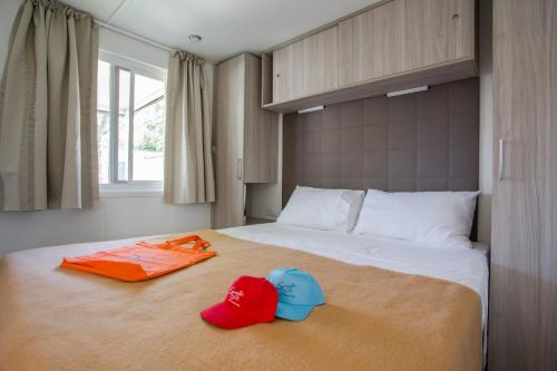 Una cama con dos sombreros y sombreros encima. en Camping Spiaggia D'Oro, en Lazise