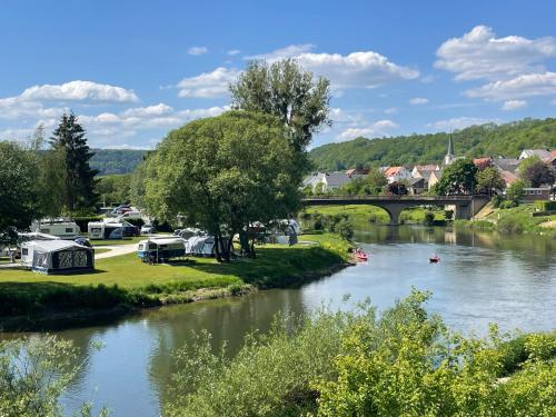 a river with a bridge and a group of tents at Camping du Rivage in Wallendorf pont