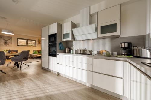 a kitchen with white cabinets and a dining room at Lindenberg Apartments in Wernigerode