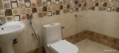 een badkamer met een wit toilet en een wastafel bij Butola Hotels in Rishīkesh