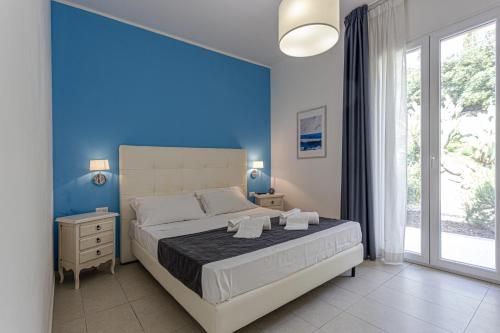a bedroom with a large bed with a blue wall at Small Luxury apartments Pool and sea view - Stella Del Mare in Fontane Bianche